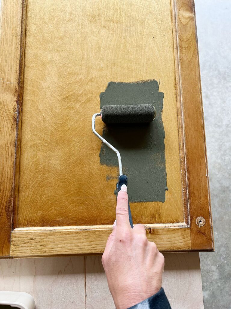painting a cabinet door outside using a roller and Emerald Urethane paint by Sherwin Williams
