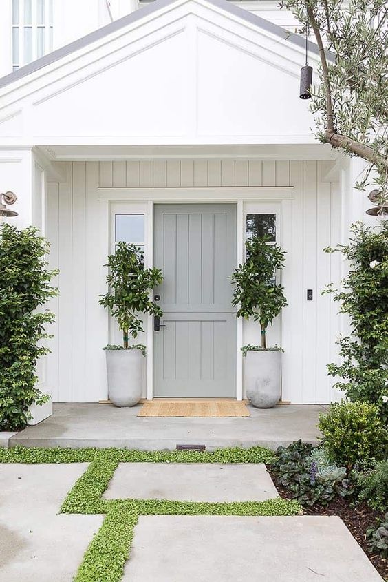 white house with grey front door and concrete planters on each side of the door