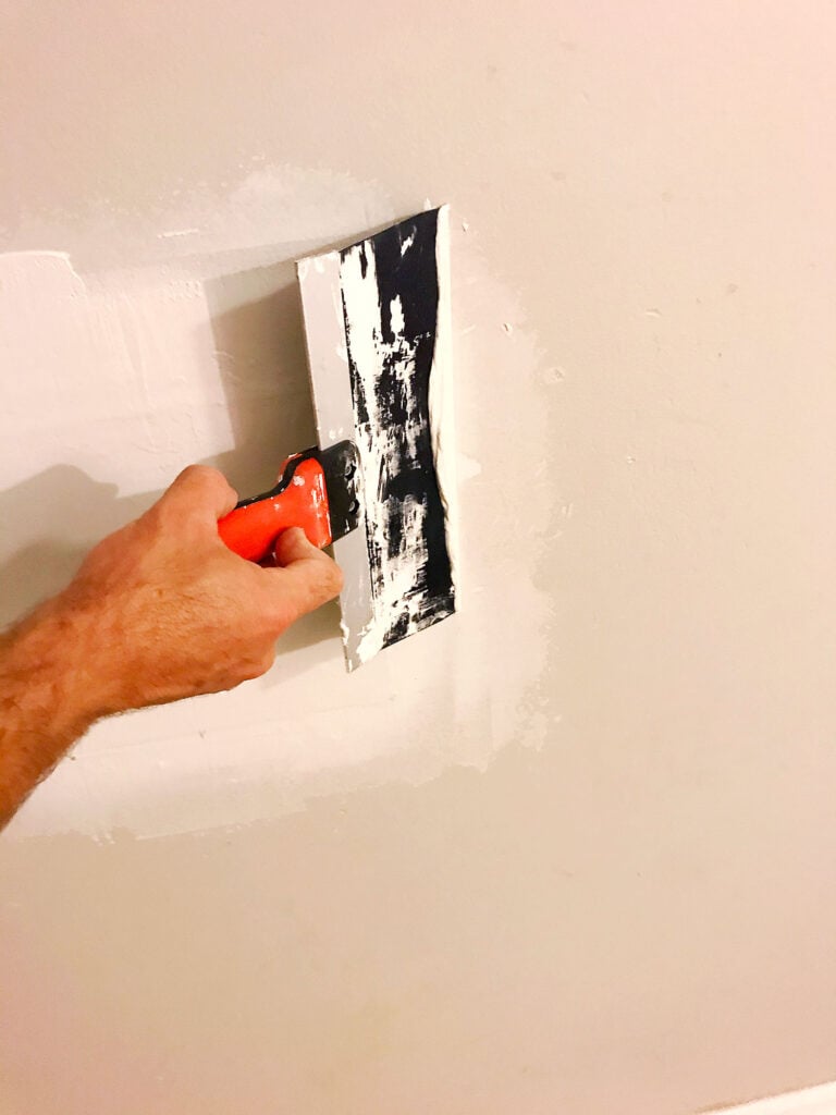applying mud over drywall patch to smooth wall surface