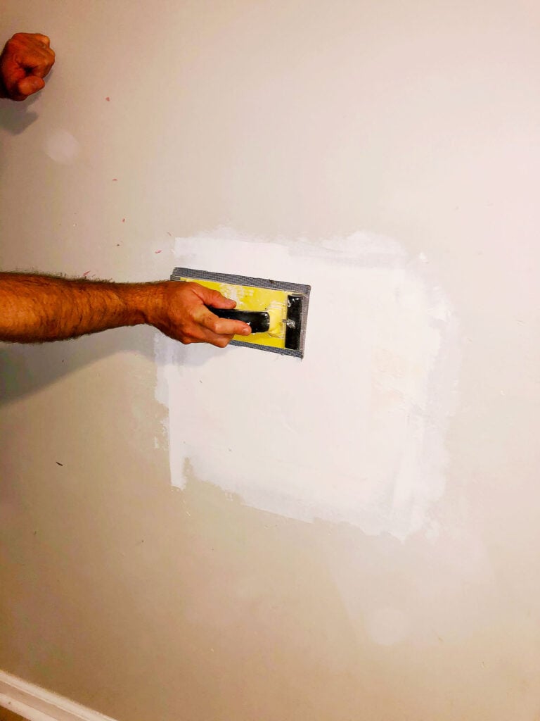 sanding down drywall mud to create a smooth patch finish