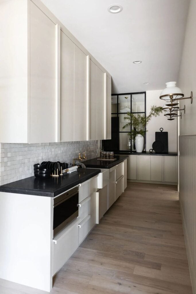 greige cabinets with black countertops and zellige backsplash