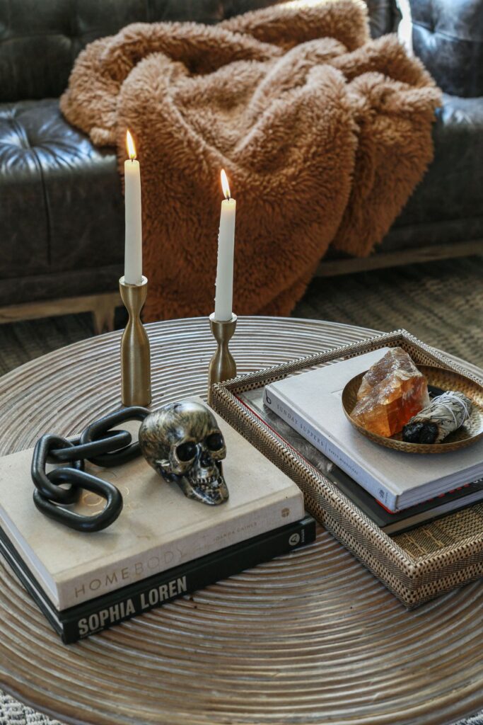 coffee table styled for halloween with elegant metal skull, brass candle holders and a crystal