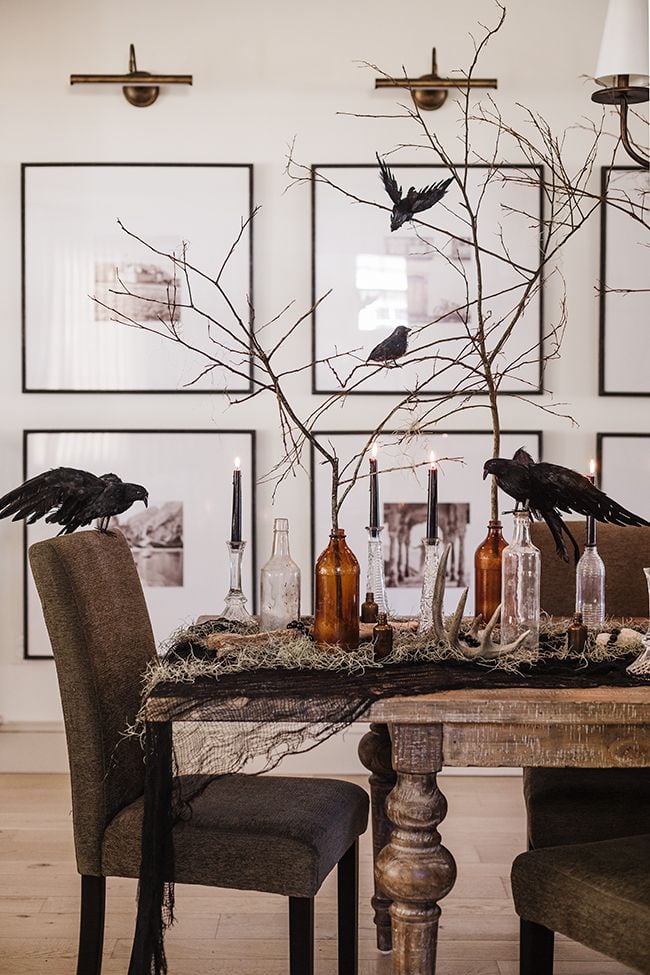 neutral elegant dining room styled with halloween decor including ravens, black candles and apothecary bottles