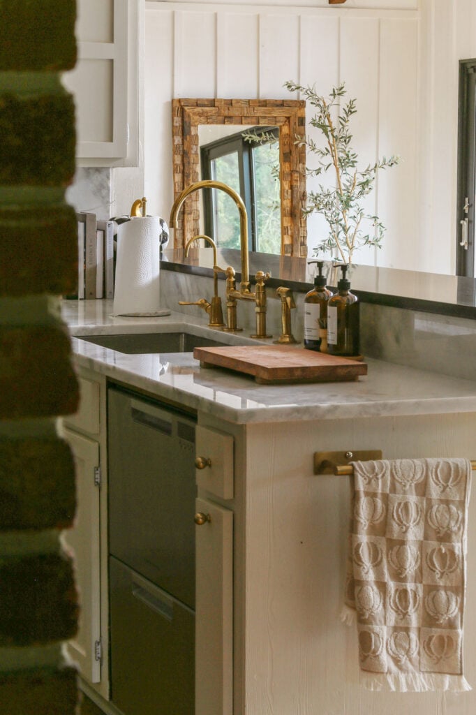kitchen with creamy beige cabinets, marble countertops and unlaquered brass faucet