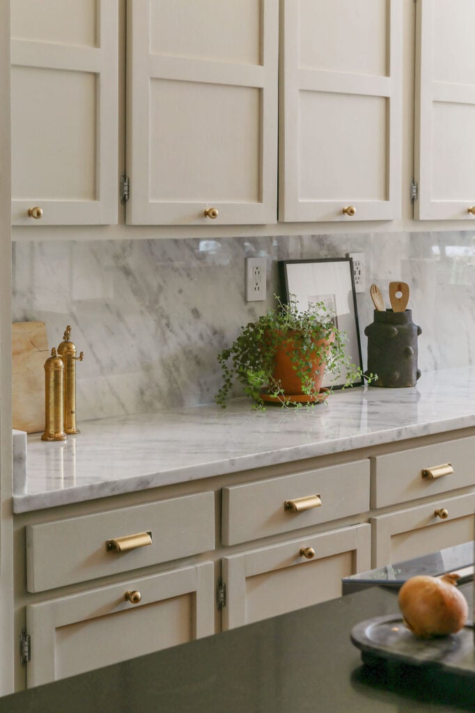 polished marble countertops and baacksplash in greige kitchen with brass hardware