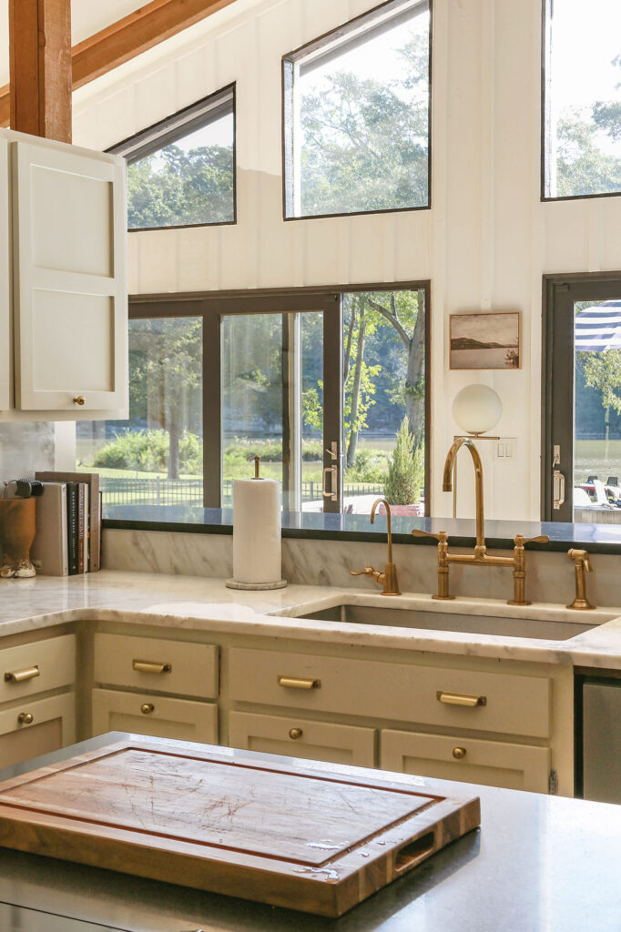 lake cottage kitchen with greige cabinets, black windows and marble countertops
