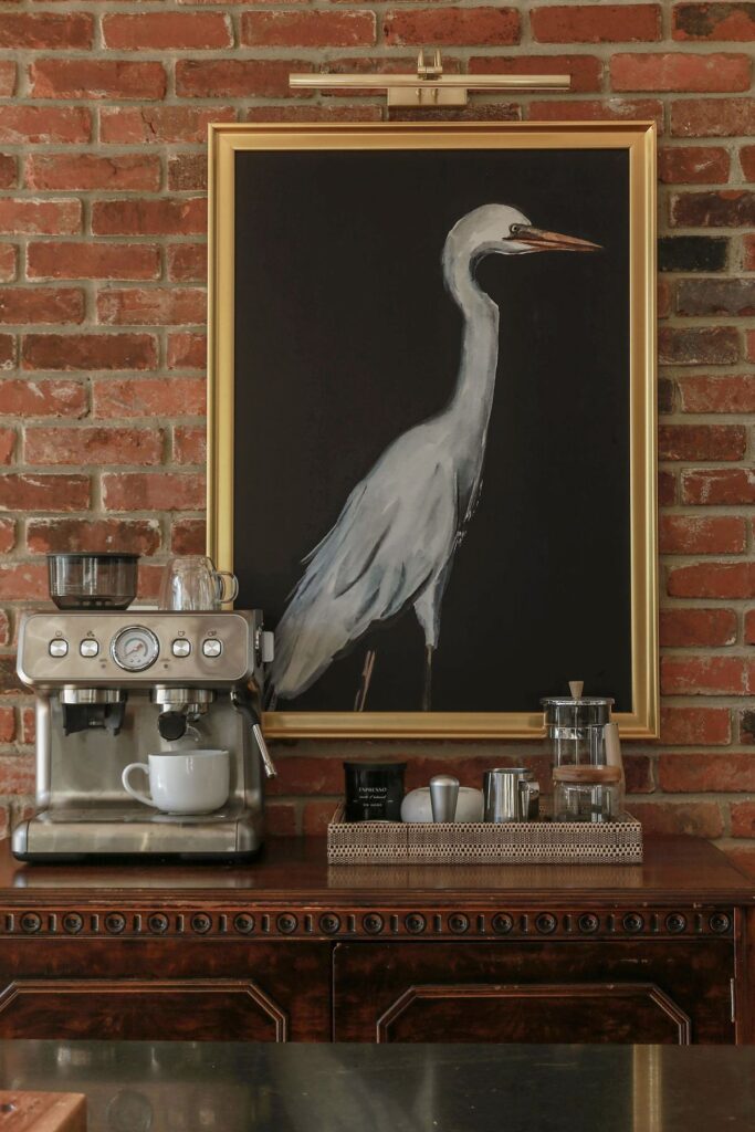 coffee bar with espresso machine on antique furniture in kitchen with marble countertops