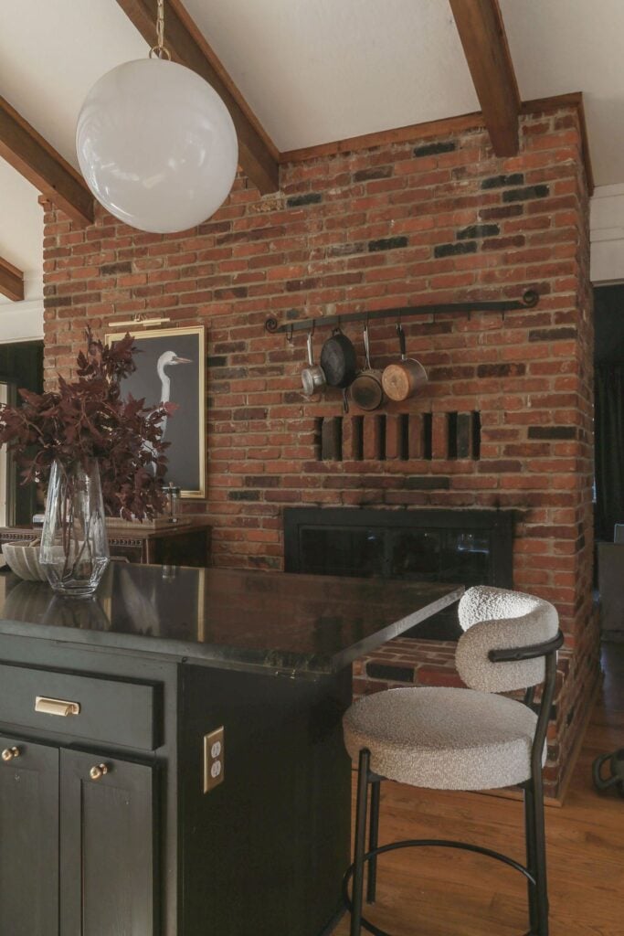 moody cottage kitchen with brick fireplace and polished marble counters
