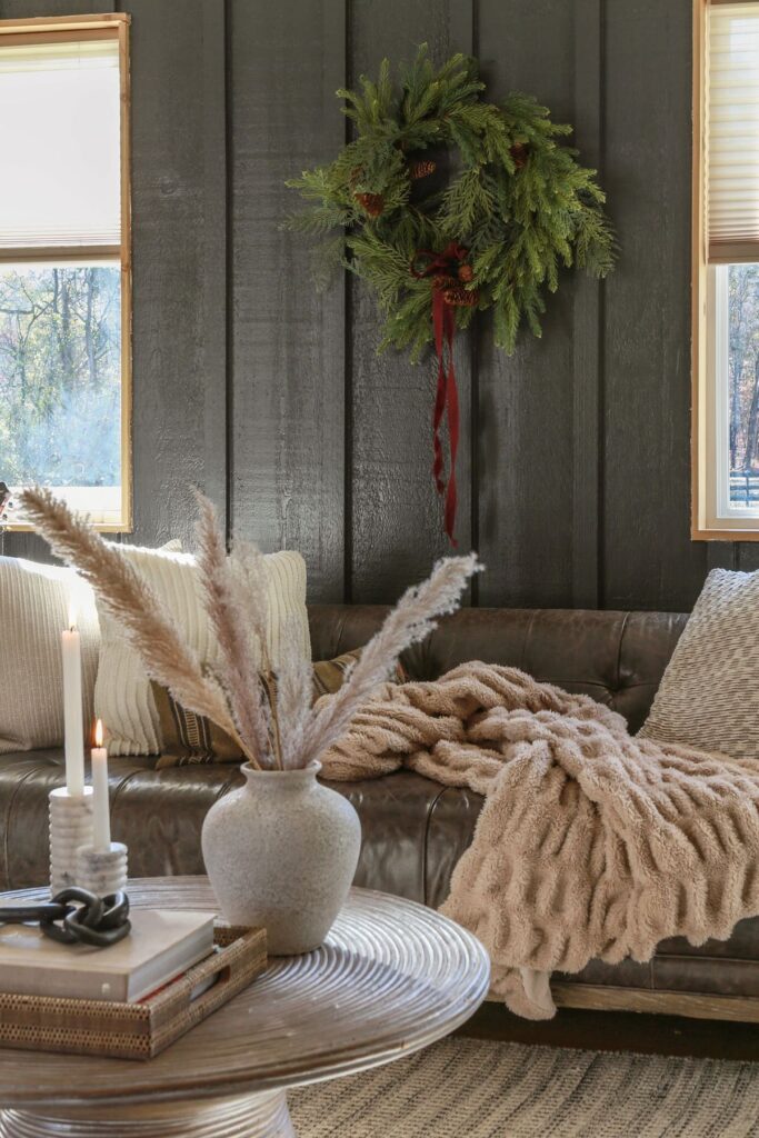 dark moody living room decorated for christmas with wreath and burgundy ribbon