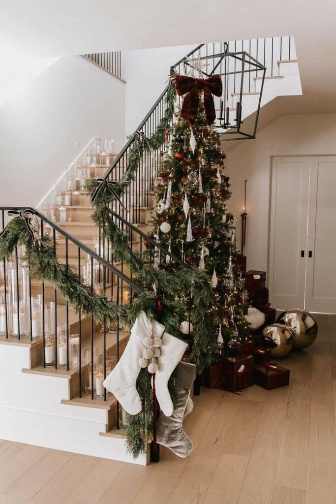 christmas tree with burgundy ornaments and bow topper along with gifts wrapped in burgundy colored paper
