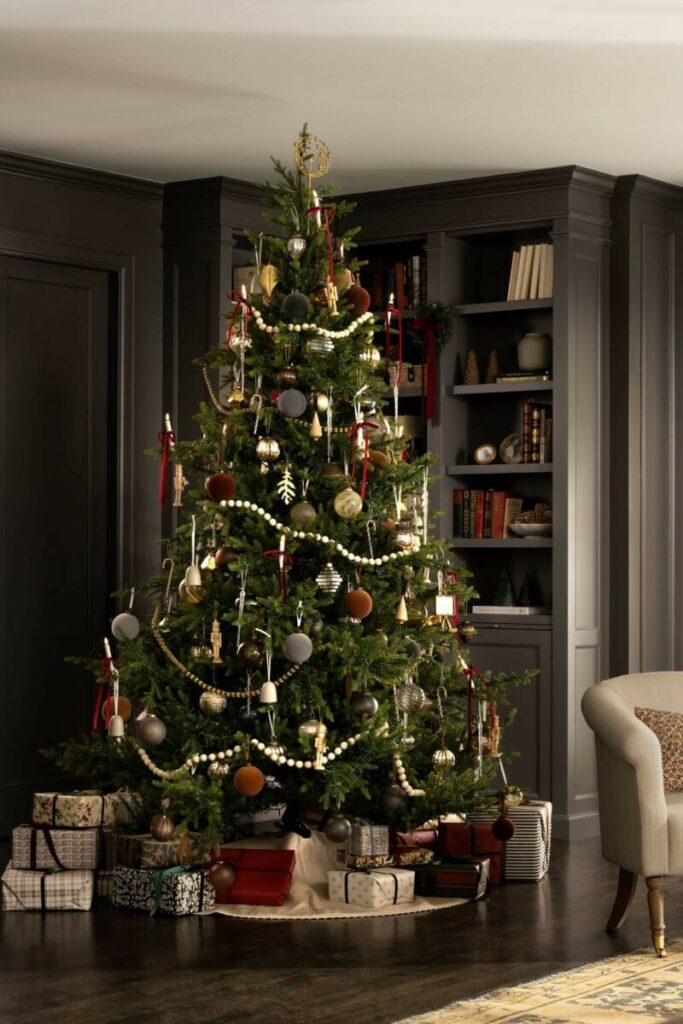 christmas tree with earth tone and ornaments and burgundy ribbon in dark moody office