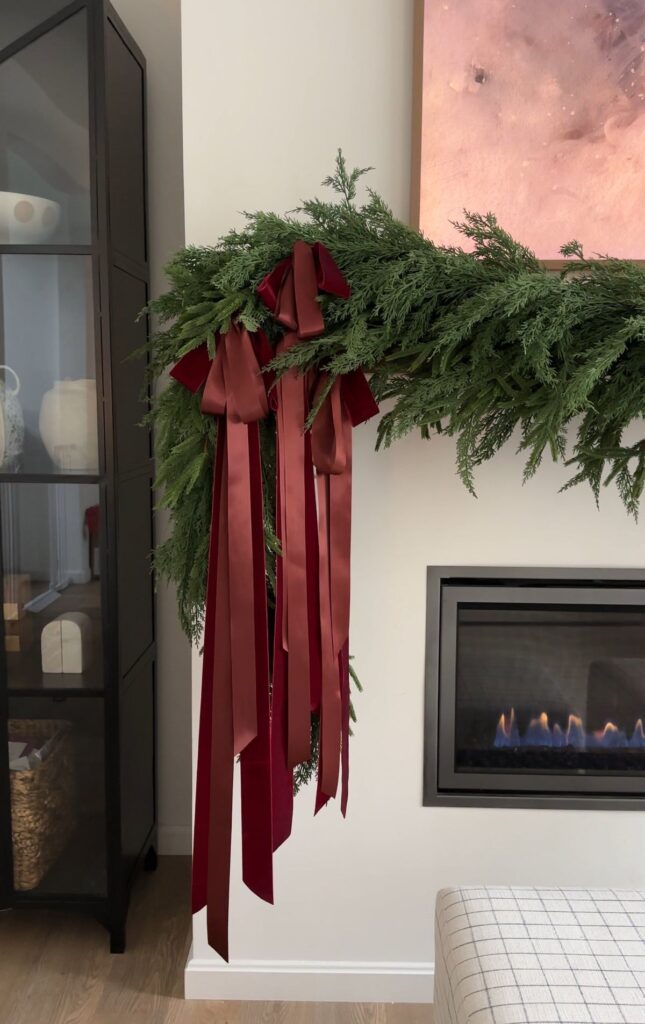 holiday mantel styled with garland and burgundy ribbon 