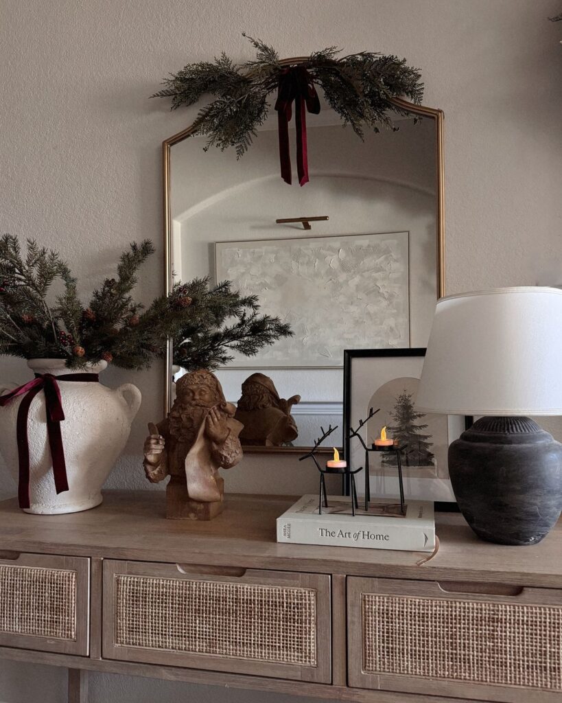 console table styled for christmas with modern organic decor and burgundy ribbons tied to garland and vase