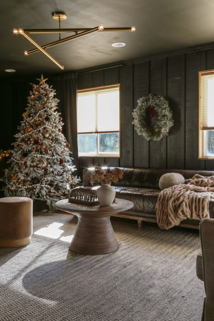 dark moody modern living room with flocked christmas tree and wreath