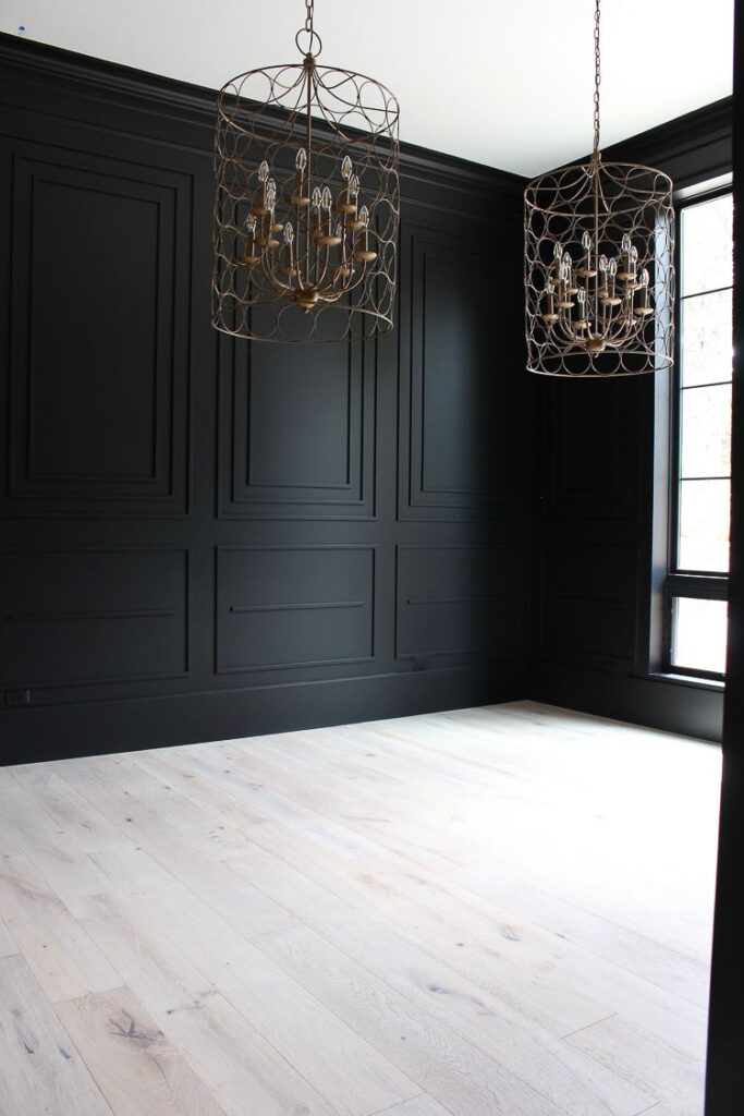 walls of dining room painted Tricorn Black by Sherwin Wiliams paired with molding and light oak floors