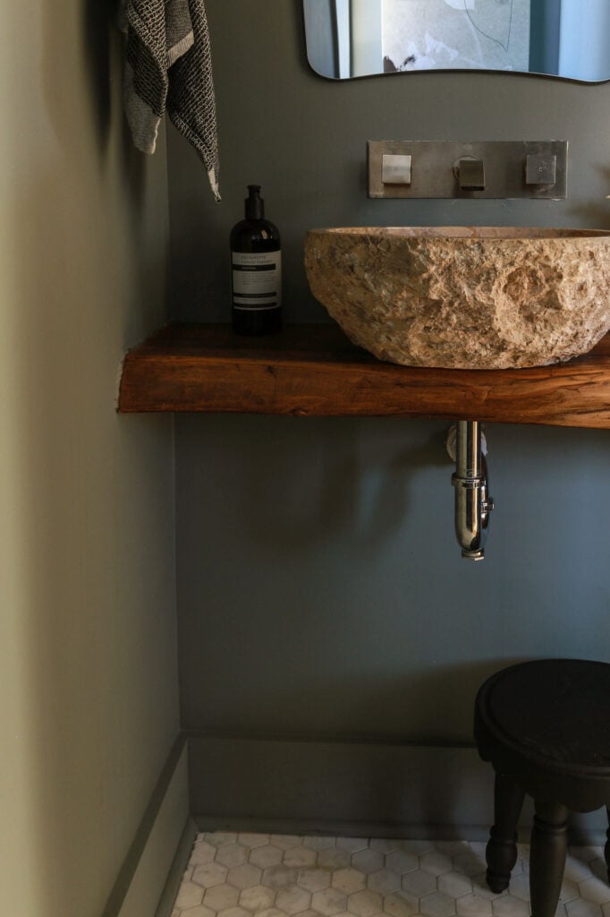 color drenched powder room with marble hex floors and stone sink