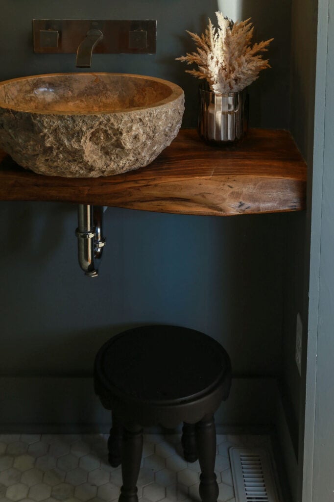 moody powder room with stone vessel sink and floating wood vanity