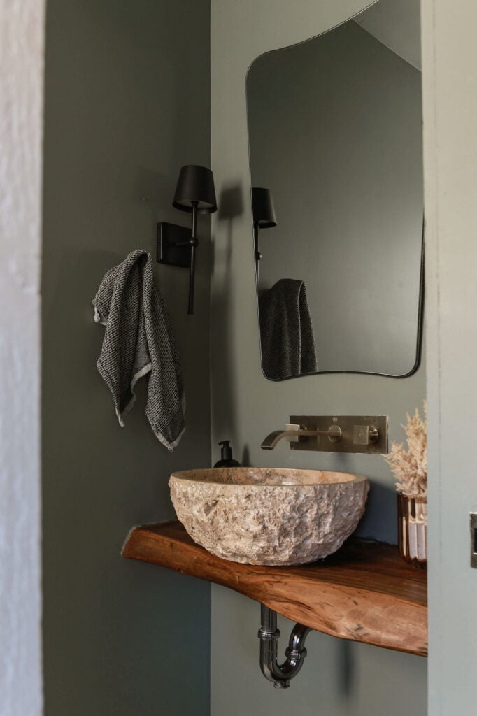 dark green powder room with black hardware and stone sink