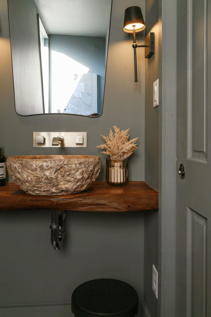 moody dark green powder room with stone vessel sink