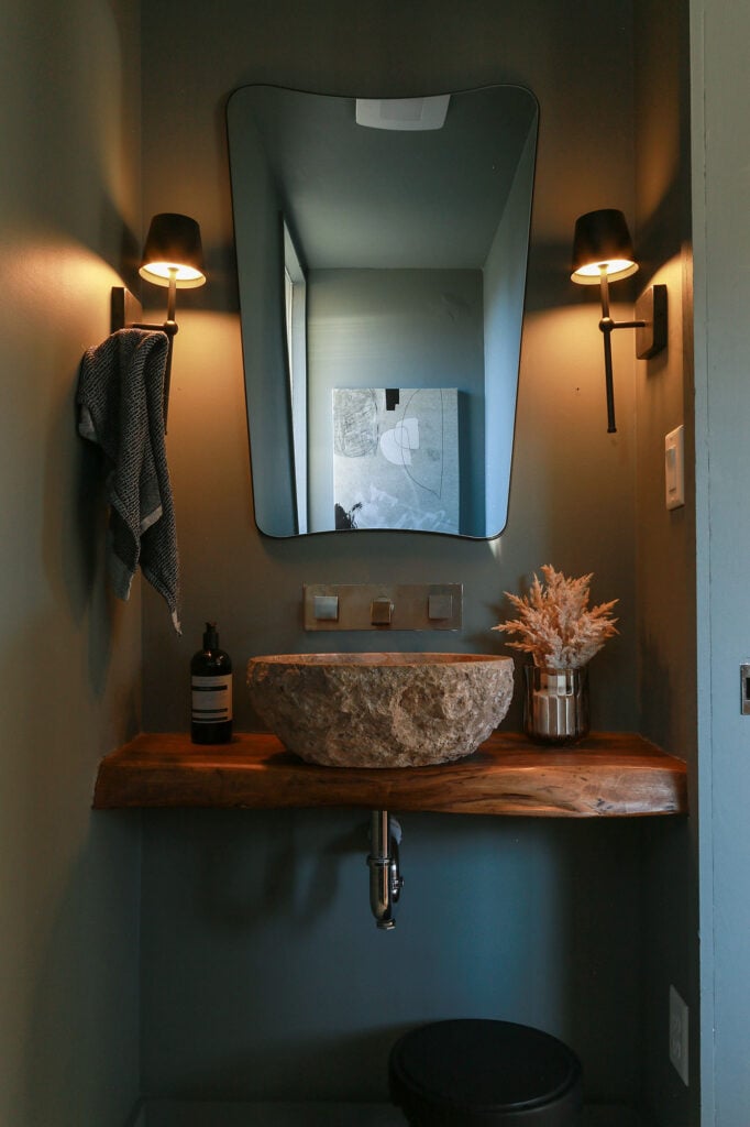 dark green powder room with stone vessel sink