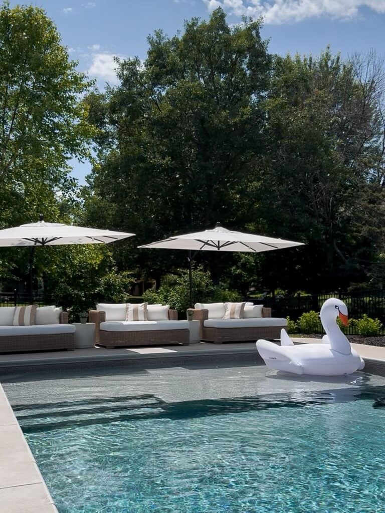 3 sofa beds with umbrella over each one sitting along pool
