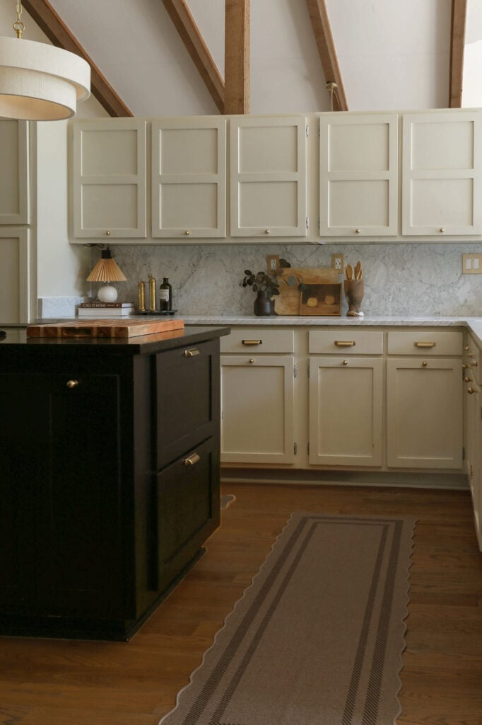 moody modern kitchen with marble counters, cream cabinets, and black island with diy drawers