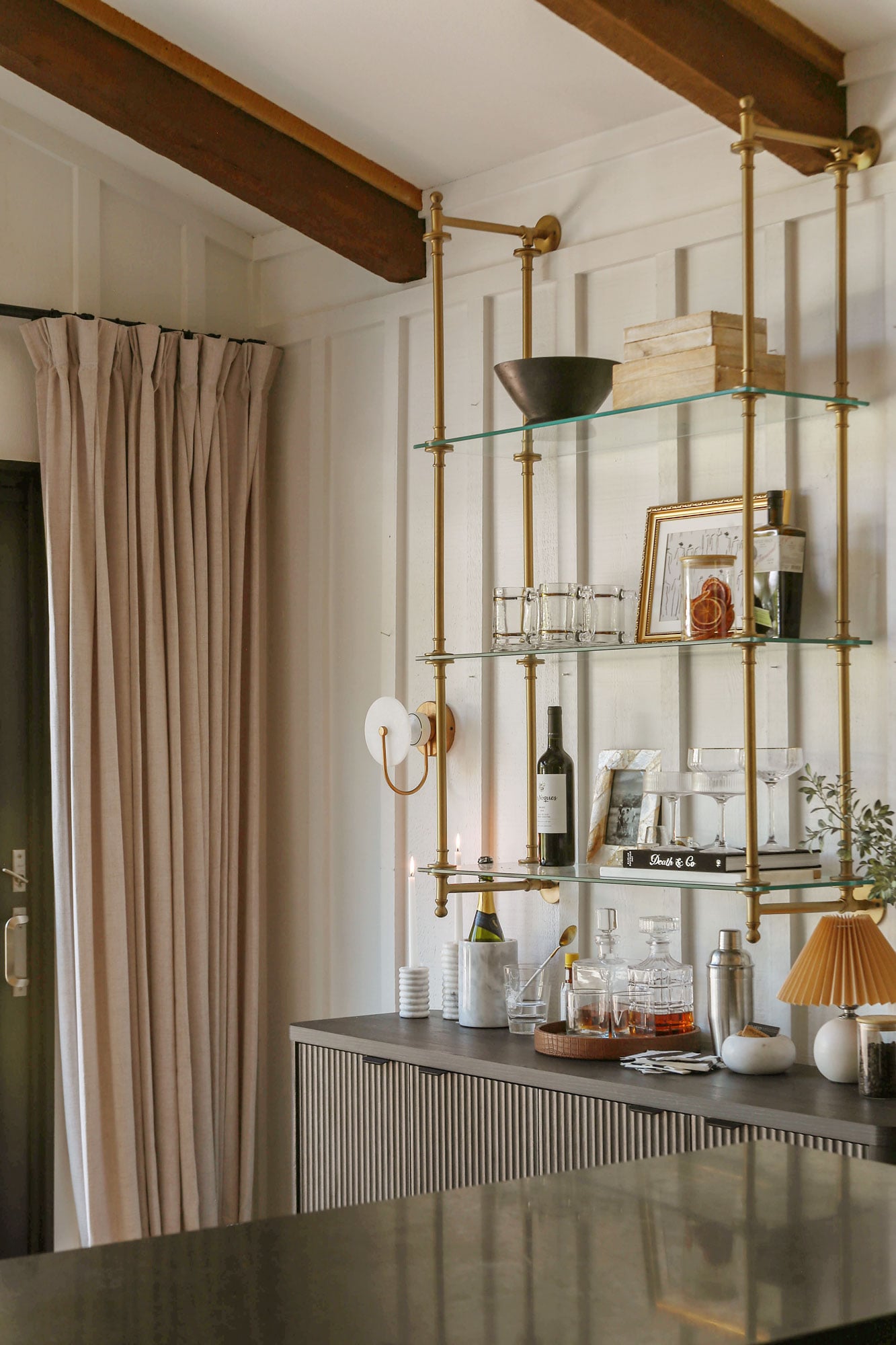 DIY kitchen bar area featuring a fluted credenza and brass bistro shelves styled with glassware, wine bottles, and liquor bottles
