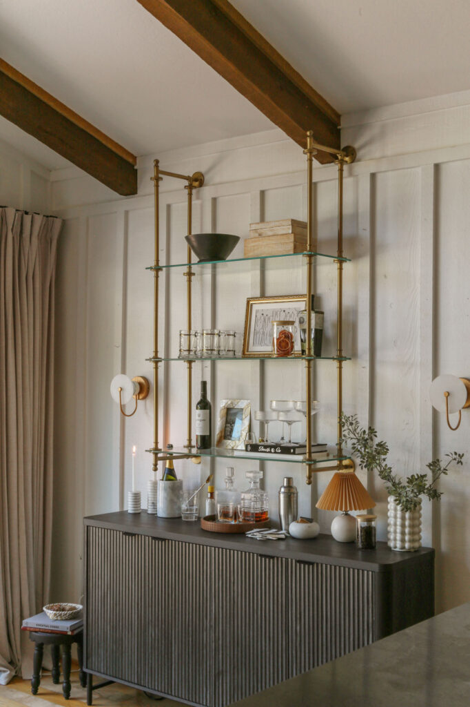 Fluted credenza styled as a home bar beneath brass bistro wall shelves