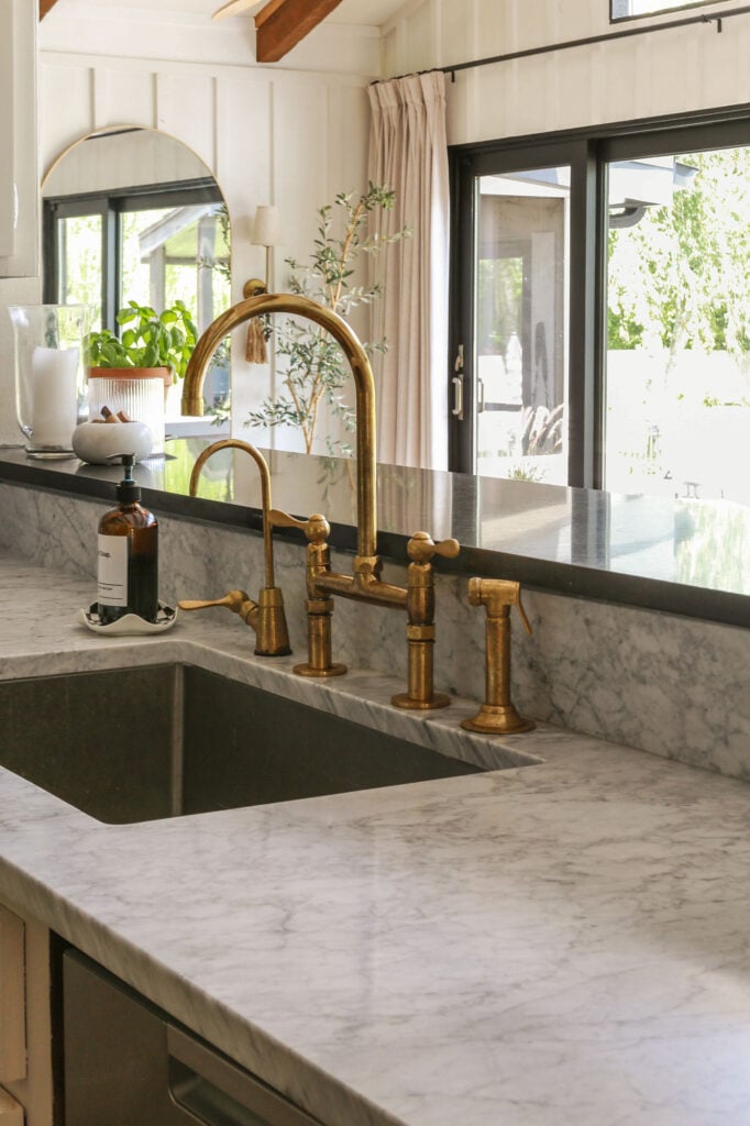 moody euro kitchen with honed carrara marble and unlacquered brass faucet