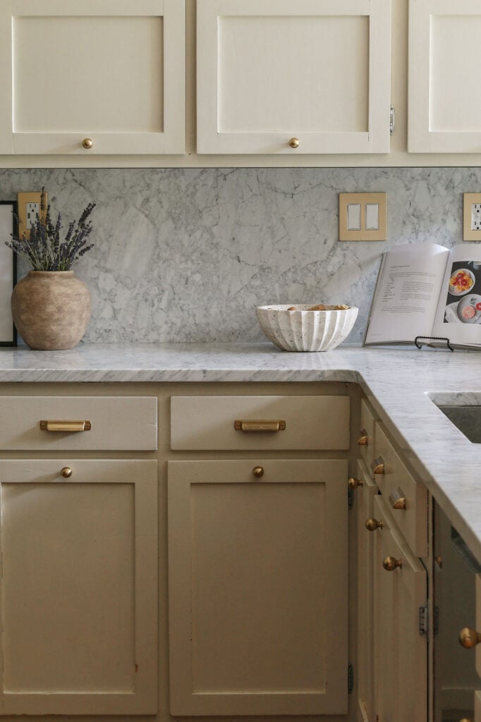 kitchen with honed Carrara marble countertops and backsplash from daltile and natural cream cabinets