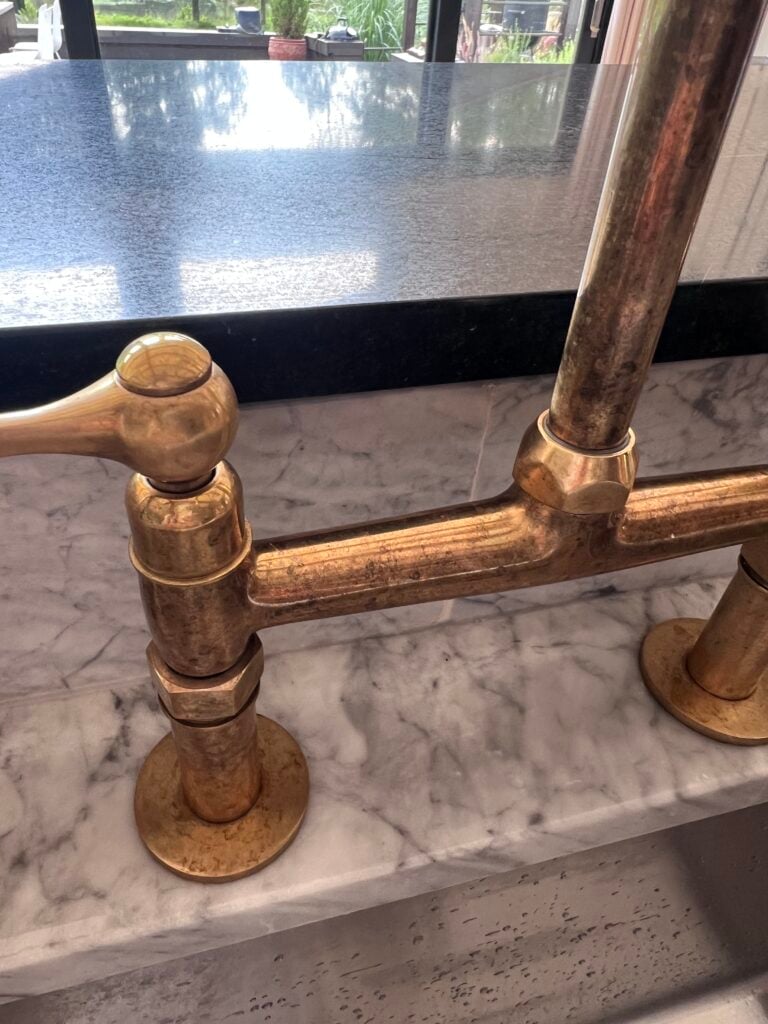 close up of water marks and patina on Unlacquered Brass Faucet after one year of use in a kitchen 