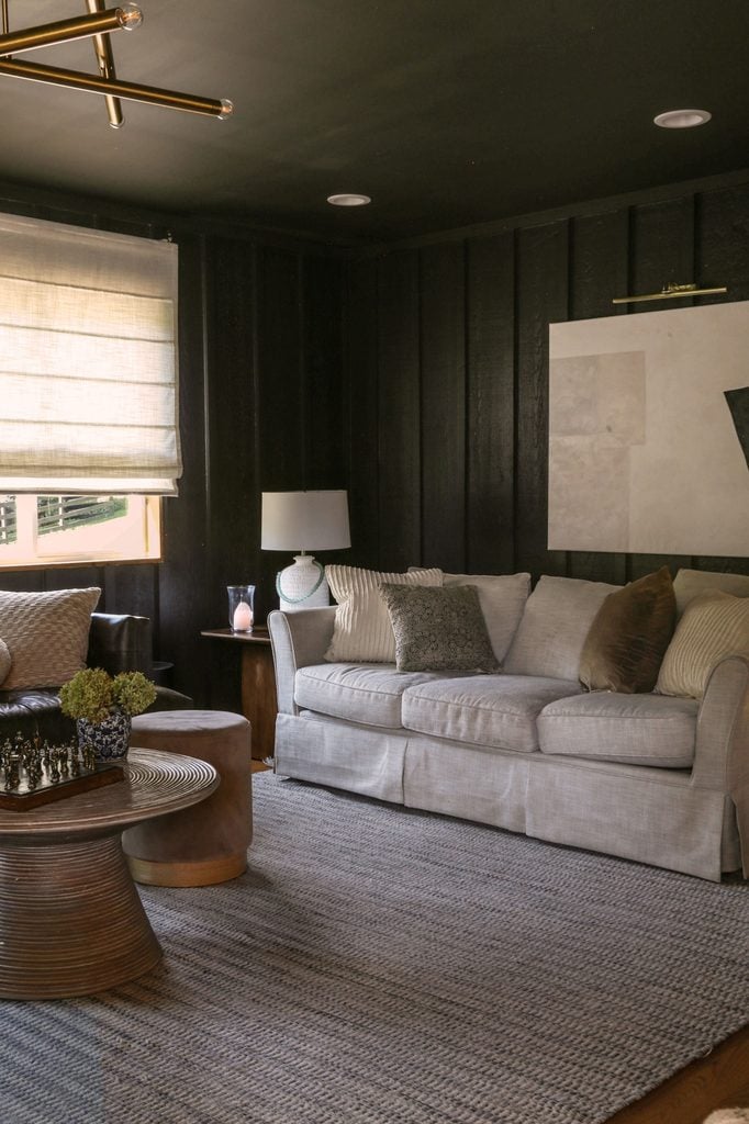 off white roman shades in dark, color drenched living room 