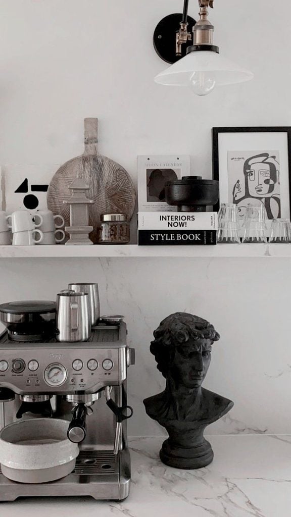 modern coffee station on marble kitchen counters with espresso maker, euro bust and open shelves with modern art